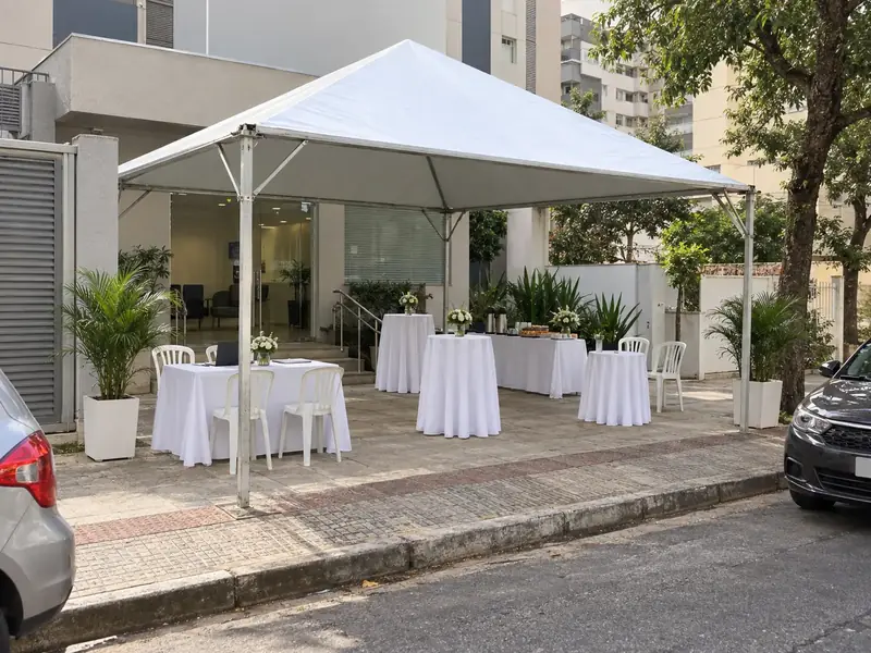 Tenda piramidal montada em frente a empresa com mesas decoradas